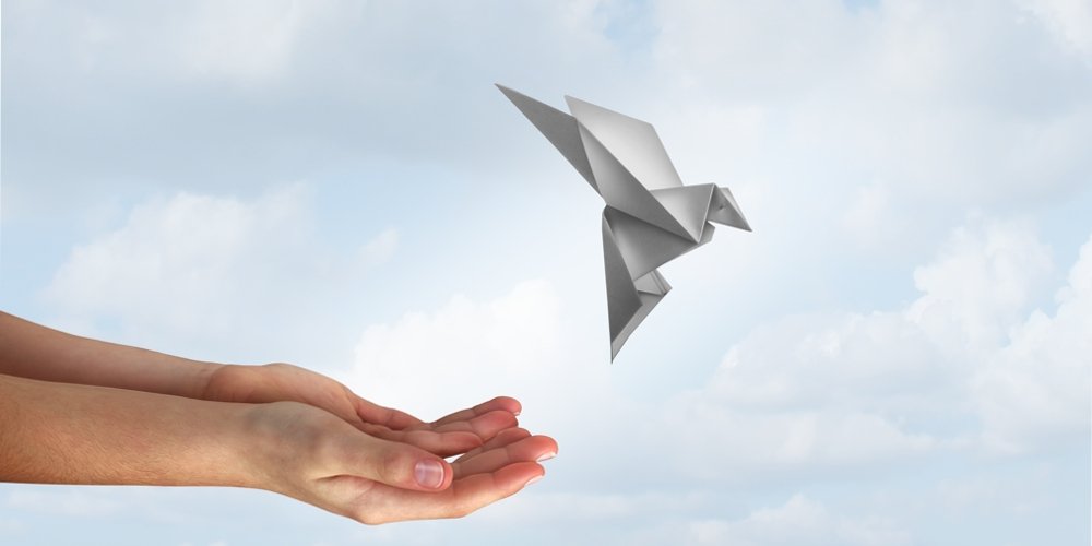 5 pieces of crumpled paper and an origami bird taking flight, symbolising helping an idea take flight